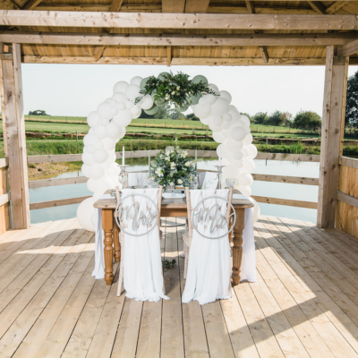 A white wedding balloon hoop, done in white balloons with added greenery