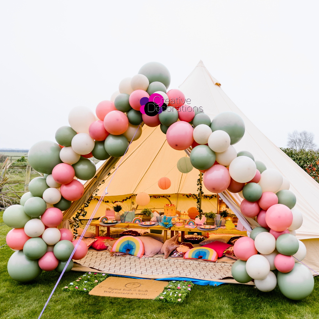 A bell Tent with a green and pink balloon garland set up for childs birthday party 
