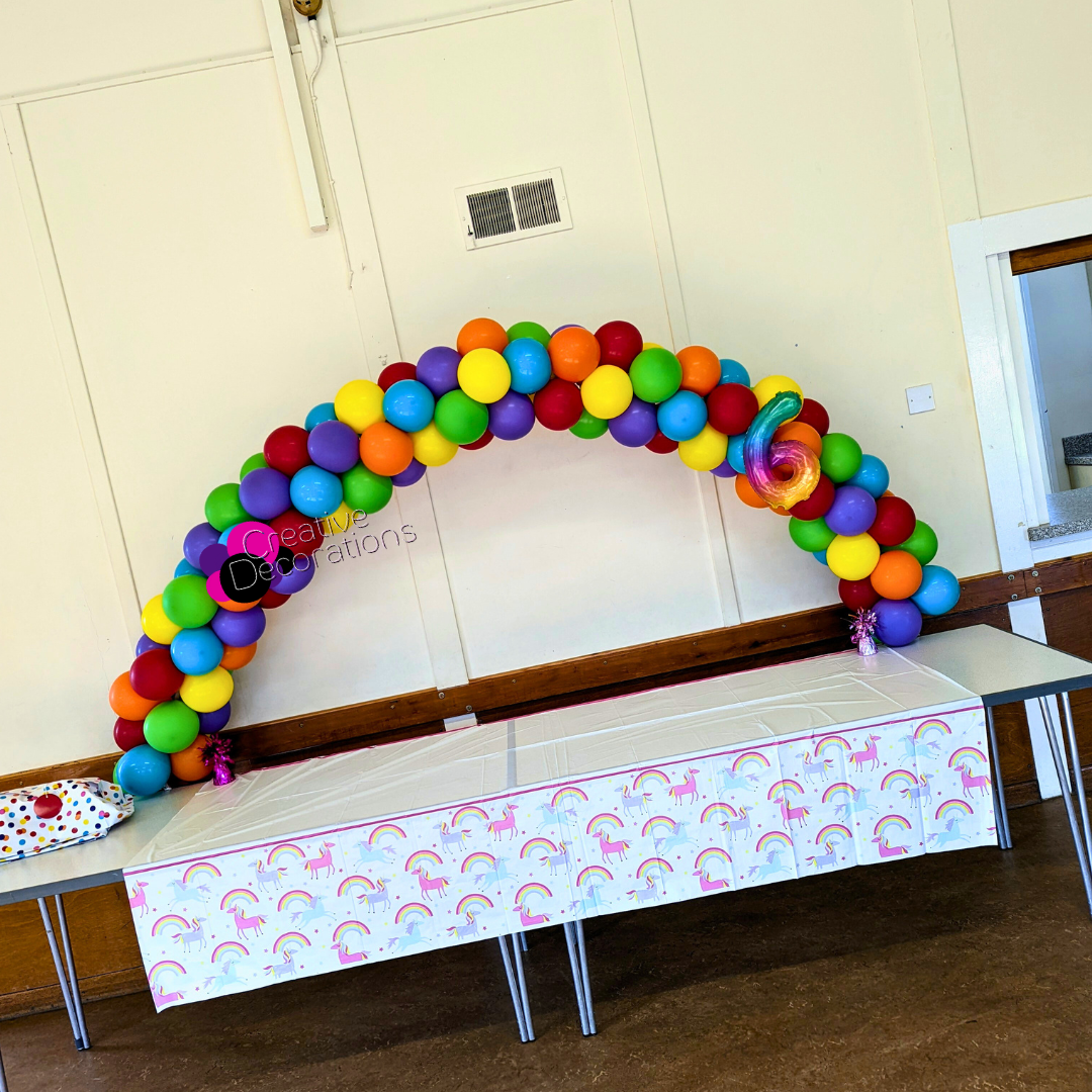 A multi coloured balloon arch for a table 
